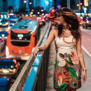 A joyful woman standing by city traffic, embodying vibrant urban life at night.